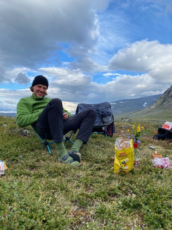 Blond man in green sweater sitting in the nature 