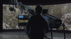 A man operating a camera in front of a large LED volume